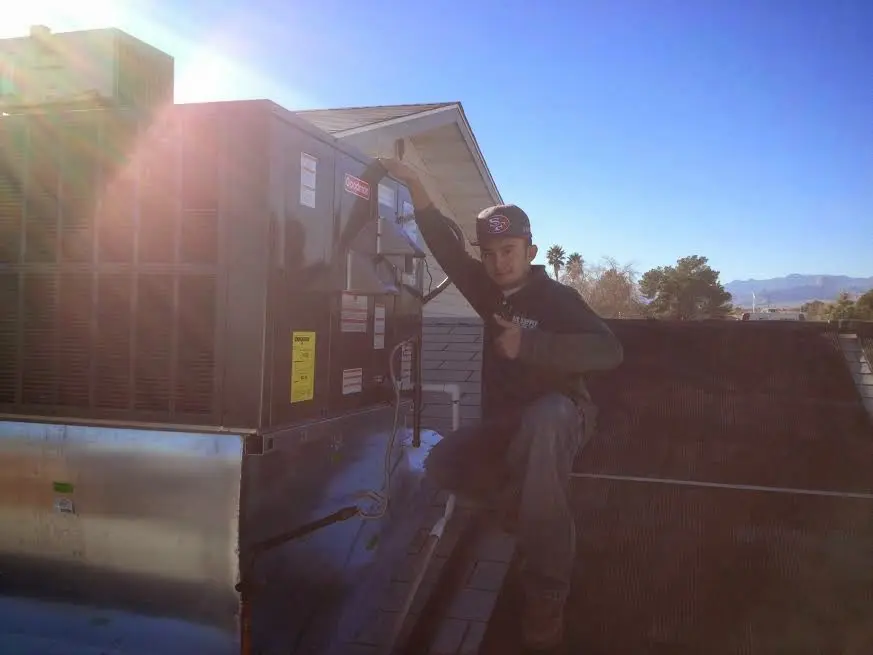 HVAC technician performing Air Duct Cleaning on a rooftop unit in Stamford